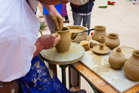 陶器制造商使用踢轮用手模制陶罐图片