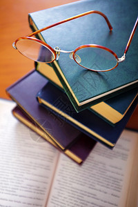 一堆旧书和一副老式眼镜在上面图片