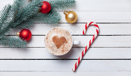 一杯有心脏形状的咖啡和圣诞糖果在白木本图片