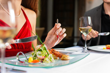 情侣共进浪漫晚餐或午餐在美食餐厅喝白酒背景图片