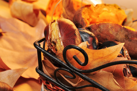 用烤栗子烤甜土豆和秋叶关闭一个生锈的篮子图片