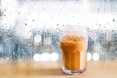 木头上的冰奶茶和背景上的雨滴图片