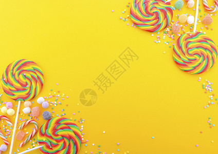 明亮的彩虹棒糖在多彩黄色的黄木桌上为万圣节特技或治图片