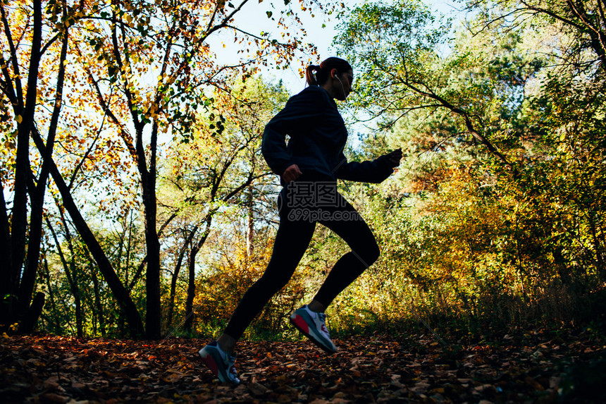 在秋天公园慢跑的女运动员图片
