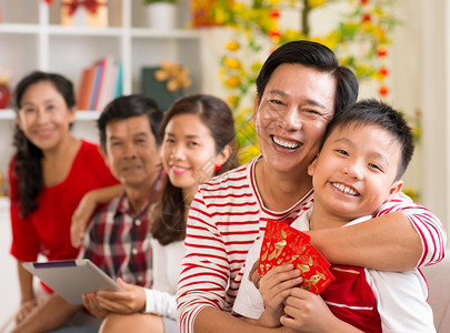 庆祝春节的幸福家庭拥抱他的儿子的愉快的父亲拿图片