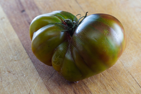 木制切菜板上绿色传家宝番茄的特写图片