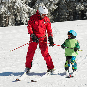 小男孩和教练一起滑雪图片