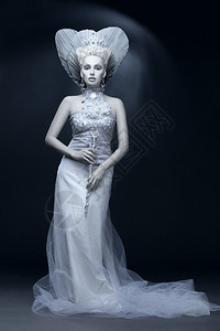 打扮成冬皇后的年轻美女的肖像创意化的妆品在黑暗背景图片