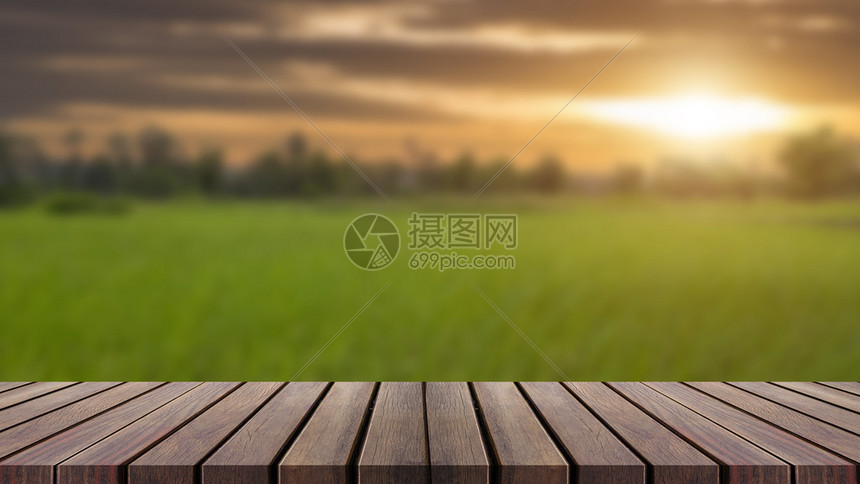 模糊蓝天空和绿草原背景的木质顶桌可以用于补假或图片