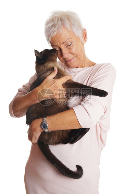 快乐的成熟女人在她的怀里抱着尖锐的猫在图片