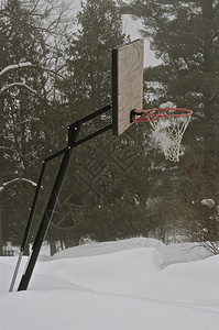 一个户外倾斜的篮球标准篮板和篮筐都被积雪包围图片