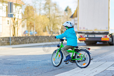 学龄前儿童男孩骑自行车在城市的道路上儿童汽车和轨图片