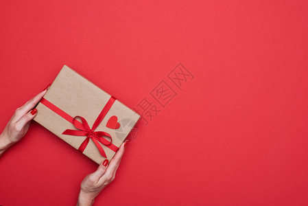 大角度手对角握着用红丝带包裹的礼物盒背景图片