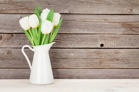 白色的郁金香花束在白壶图片