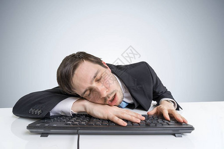 疲惫或疲惫过度劳累的商人正在键盘上睡觉图片