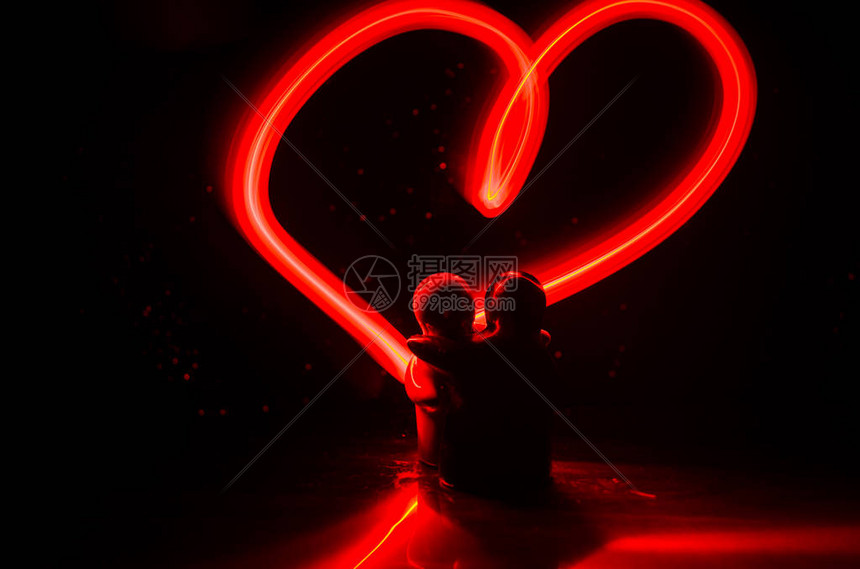 两个年轻的恋人用火描绘了一颗心情侣和爱情词在深色背景上的图片