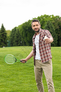 快乐的活跃男子玩羽毛球在公园里用花冠和穿梭图片
