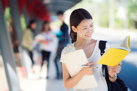 大学亚裔女学生走在步行路上手拿电图片