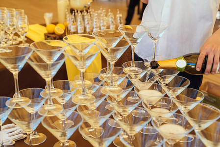 满杯百香果在婚礼派对上盛满玻璃香槟的金字塔香槟杯男酒保把香背景