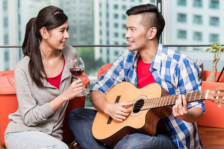 年轻男子在城市公寓同居后在吉他上为女友图片