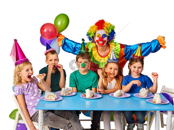 生日儿童小丑和吃蛋糕的孩子一起玩一群人为相机摆姿势的乐趣坐在桌子的白色背景上在假期图片