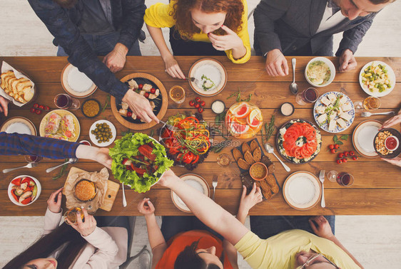 人们在为聚会服务的节日餐桌上吃健康的饭菜朋友们在木桌顶视图上用有机食品庆祝快乐的公司吃午图片