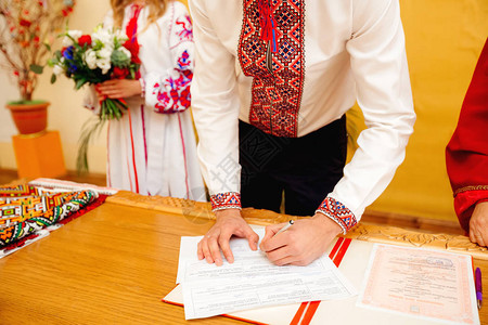 新郎在结婚登记文件上签字年轻夫妇签署婚礼文件男人高清图片