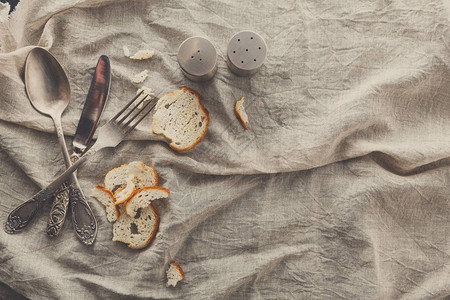 餐具与旧织物顶视图上的面包和香料用刀勺和叉就餐的乡村背图片