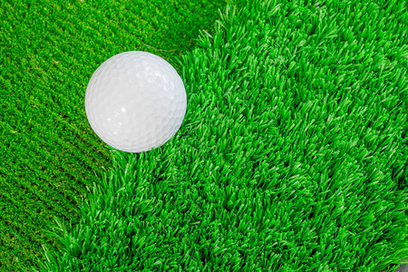 绿色人工青草上的白色高尔夫球练习将粗野和绿色的图片