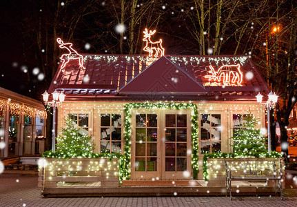 有装饰的木小屋在晚上圣诞节圣诞橱窗外的圣诞树里图片