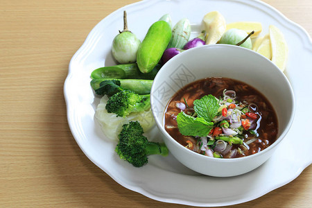 在木地板上的碗里放着酸辣沙拉的泰国菜腌贻贝图片