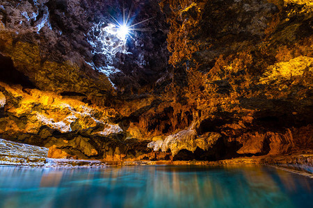 光线从地下洞穴的一个开口照射到洞穴和盆地历史遗址的温泉水中图片