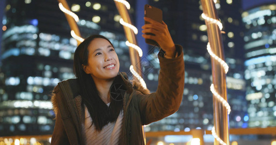 晚上在城市用手机直播的女人晚上美丽的图片