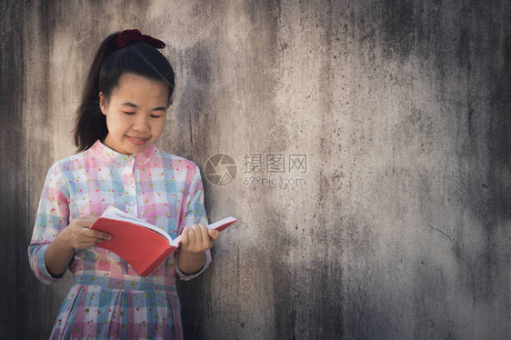教育和知识概念美丽的亚洲年轻女阅读深水泥墙背景书籍图片