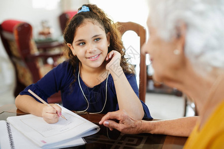 快乐的小女孩在家和老妇人一起做学校作业与祖母和孙女的家庭关系奶图片