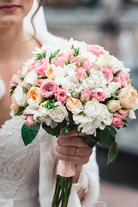 新娘穿着豪华的婚纱带着用白橙和玫瑰制图片