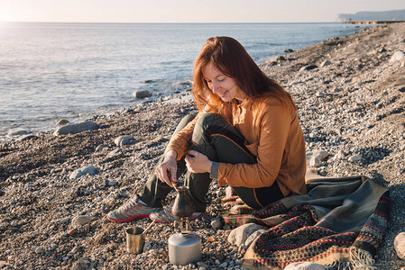 年轻女子在海滩上煮咖啡享受美图片