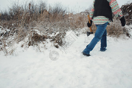 一个手拿着斧子的男人在雪路上行走开图片