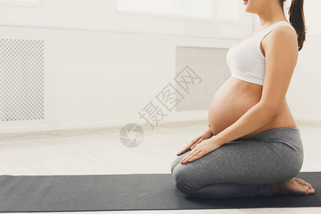 无法辨认的孕妇在英雄姿势中训练瑜伽图片