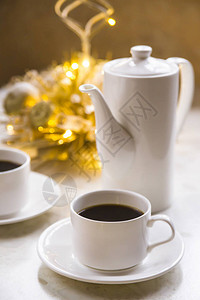 白色杯子和茶壶黑色咖啡在灯光和家图片