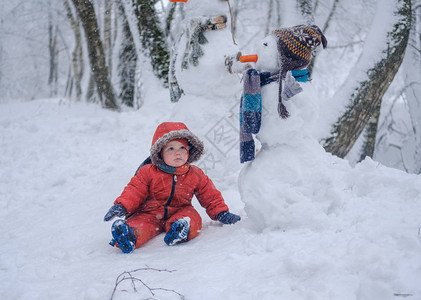 冬日雪地里可爱的欧洲男孩和雪地树林图片