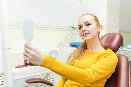 在口腔诊所接受牙科治疗后年轻女在镜背景