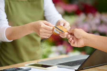 无法识别的客户在花卉店用信卡支付购货费的近镜头图片