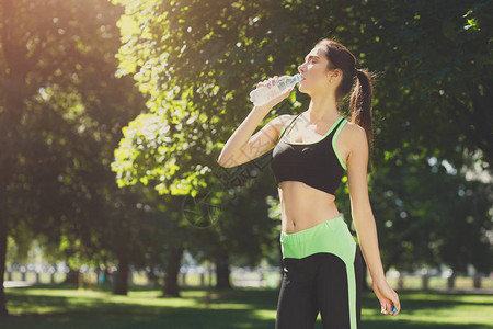筋疲力尽的女人在户外训练后穿着服从瓶子里喝水舒展健康平静放松积极的背景图片