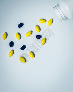 黄色椭圆形药片和黑色药片从药瓶中溢出图片
