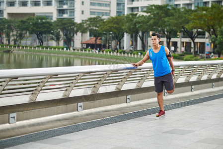 自信的亚洲运动员在城市公园慢跑前先进行热身锻图片