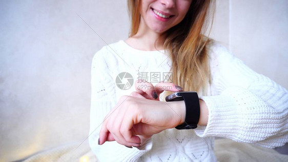 漂亮的年轻女子调整并测试戴在手臂上的小工具女人微笑着带手指沿着现代电子钟的小触摸屏长着金发图片
