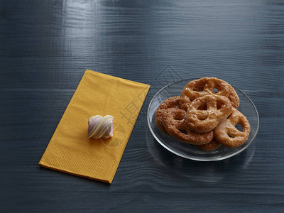 在透明玻璃盘上自制饼干和在彩色木桌餐巾纸图片