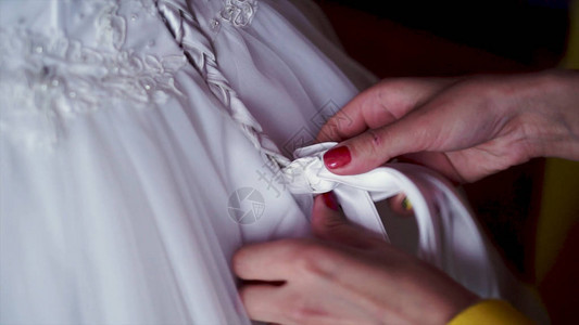 伴娘在婚纱上系蝴蝶结夹子伴娘在新娘婚纱的背面做蝴蝶结图片