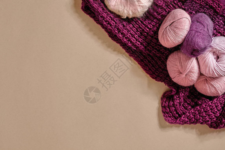 毛线帽子毛线球和织针用于在米色背景的柳条碗中编织的彩色纱线针织作为一种针线活五颜六色的背景